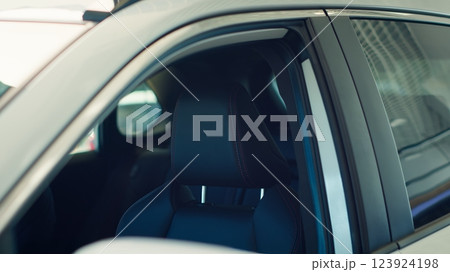 Exterior detail close up of steel white car body door post, windows, and driver chair inside. Panning shot of parked vehicle and leather black seat in automobile interior Exterior detail close up of steel white car body door post, windows, and driver chair inside. Panning shot of parked vehicle and leather black seat in automobile interior 123924198