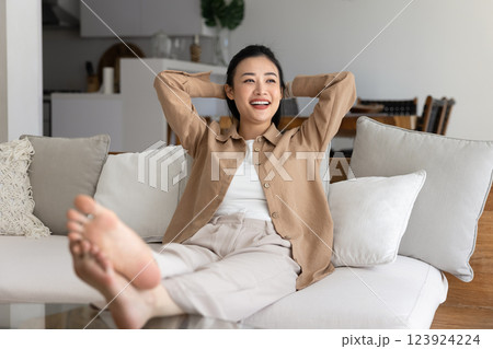 Relaxed young Asian homeowner woman resting on soft couch 123924224