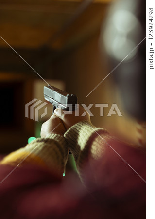 Firing range customer doing shooting activity with pistol during leisure time. Close up of person in shooting gallery learning how to use firearm, pointing it to targets to hit bullseye 123924298