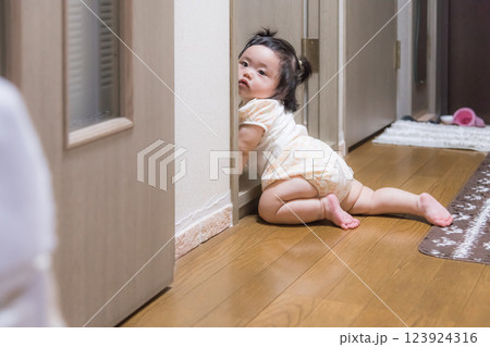 【廊下ではいはいをする髪を結んだ赤ちゃんが覗き見する】 123924316