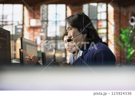 Senior call center agent using headphones microphone to answer customers technical inquiries about hardware issue. Experienced Asian worker doing customer support job using PC to troubleshoot problems 123924336