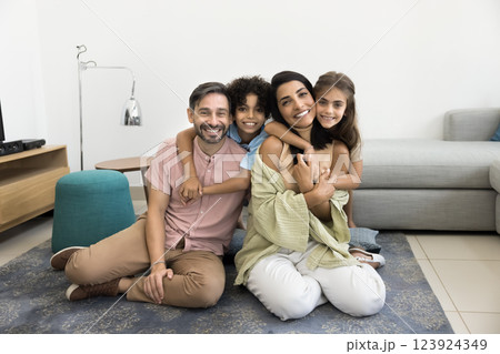 Two pretty little kids cuddling beautiful multiethnic parents 123924349