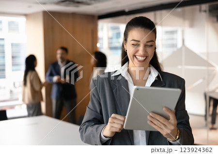 Excited cheerful young businessman using tablet in office meeting space Excited cheerful young businessman using tablet in office meeting space 123924362