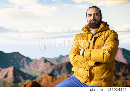 Portrait of male trekker in warm clothing takes in the sweeping mountain scenic view, sense of freedom that comes with high altitude exploration. Nature lover enjoys fresh air and wilderness. 123924363