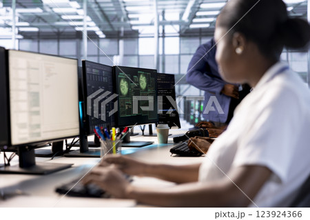 Computer scientist reconfiguring server farm to optimize it for data processing requirements of customers. African american woman working to ensure data center equipment operates efficiently 123924366