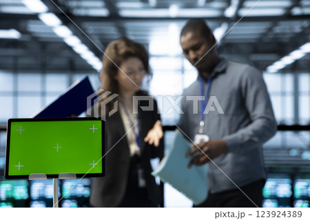 Close up of green screen tablet in front of employees overseeing server room, reading paperwork, troubleshooting hardware. Mockup device next to server hub workers reading technical files Close up of green screen tablet in front of employees overseeing server room, reading paperwork, troubleshooting hardware. Mockup device next to server hub workers reading technical files 123924389
