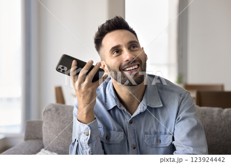 Smiling man holding smartphone listening received audio message 123924442
