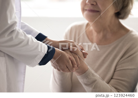 Caring doctor nurse caretaker hold sick elderly person hands closeup Caring doctor nurse caretaker hold sick elderly person hands closeup 123924460