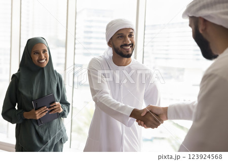 Arabian businessmen in traditional kandoras shaking hands Arabian businessmen in traditional kandoras shaking hands 123924568