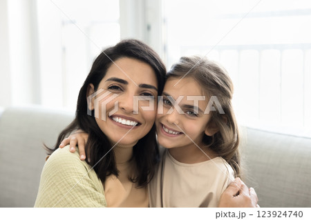 Closeup portrait beautiful mother and daughter cuddling seated on couch Closeup portrait beautiful mother and daughter cuddling seated on couch 123924740