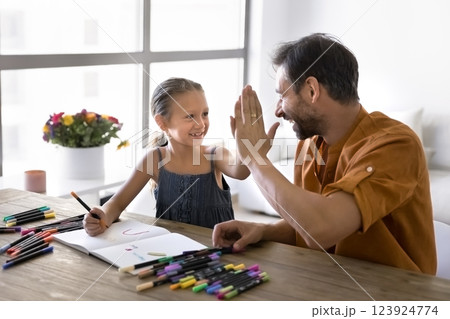Dad giving high-five to daughter while drawing with markers Dad giving high-five to daughter while drawing with markers 123924774