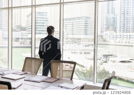 Rearview of businessman gazing thoughtfully out window at cityscape Rearview of businessman gazing thoughtfully out window at cityscape 123924808