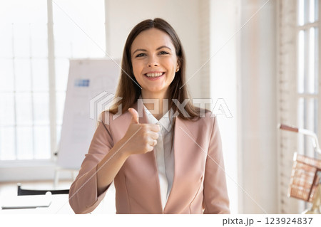 Businesswoman smiling at camera and giving thumbs-up gesture 123924837