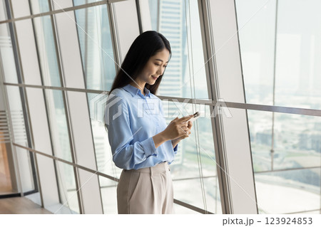 Smiling confident millennial Asian woman office employee use smartphone app Smiling confident millennial Asian woman office employee use smartphone app 123924853