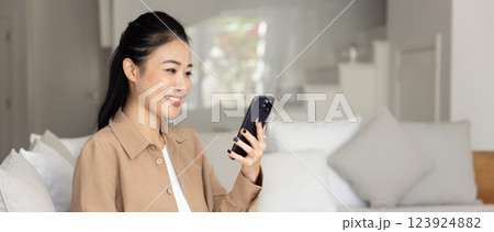 Cheerful attractive young Asian smartphone user girl using online application 123924882