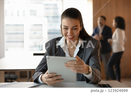 Positive successful young business woman watching online content on tablet 123924899