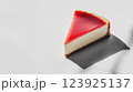Cheesecake slice with glossy red topping on white background 123925137