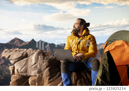Tech savvy hiker having a technology obsession and working on a mountain peak, always connected to the internet with strong signal. Workaholic traveler does remote work on a hill. Tech savvy hiker having a technology obsession and working on a mountain peak, always connected to the internet with strong signal. Workaholic traveler does remote work on a hill. 123925214