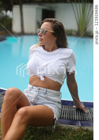 Embracing the Summer Vibes A Chic Woman Lounging Gracefully by the Poolside Under the Sun 123926686