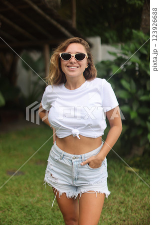 A woman in sunglasses and a white crop top is in the grass 123926688