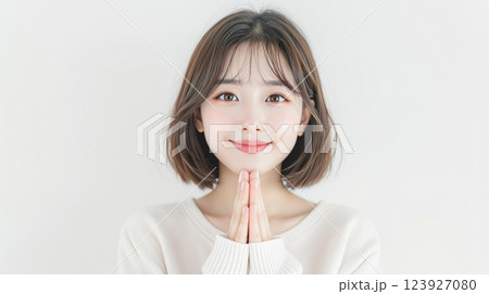 白背景に可愛く手を合わせる笑顔の若い女性 123927080