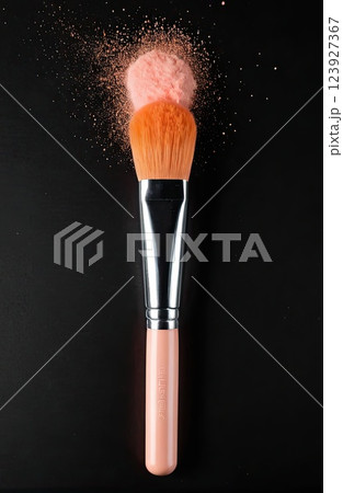 Make-up brush with Peach Fuzz powder explosion isolated in a black background with Generative AI. 123927367