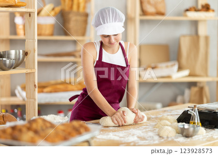 Teenage girl baker kneads the dough in bakery Teenage girl baker kneads the dough in bakery 123928573