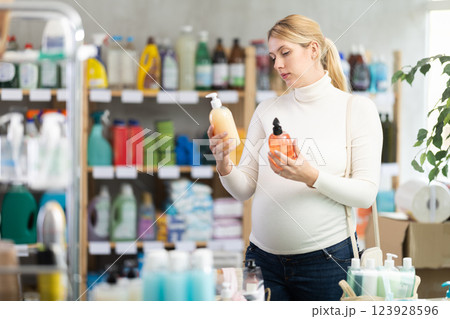 Interested pregnant woman choosing liquid soap in supermarket Interested pregnant woman choosing liquid soap in supermarket 123928596