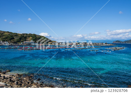 岬の見えるエメラルドグリーンの美しい海にいけすが浮かぶ海岸 123928706
