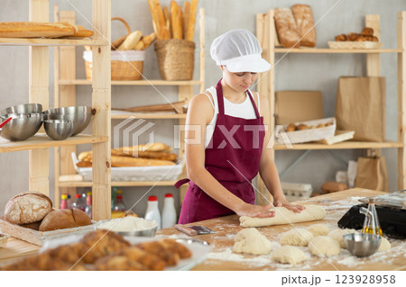 Teenage girl rolls out dough in bakery 123928958