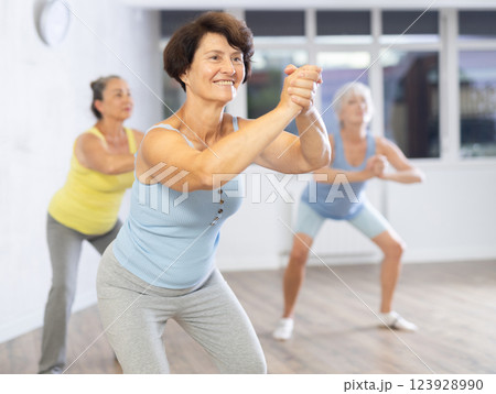 Happy mature woman practicing dance positions during workout session 123928990