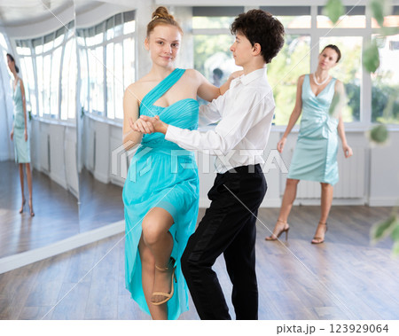 Couple of teenage dancers rehearsing ballroom dance with female teacher Couple of teenage dancers rehearsing ballroom dance with female teacher 123929064