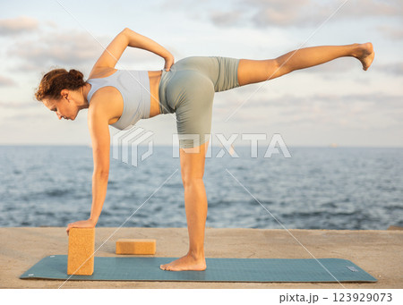 Female yoga instructor performing various asana poses using rectangular blocks 123929073