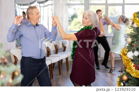 Group of adult active people dancing twist or rock and roll dance in dance hall during celebration Christmas and New Year 123929110