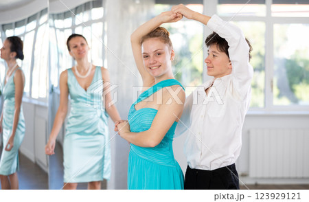 Couple of teenagers in festive clothes learn to dance latin american dance Bachata in studio under the guidance of teacher 123929121