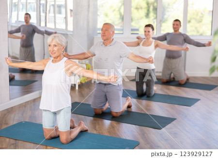 Mature woman bring together and spread your straightened arms at chest level with resistance band 123929127