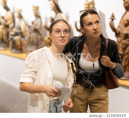 Young woman with teen daughter walk around museum, view sculpture in museum hall Young woman with teen daughter walk around museum, view sculpture in museum hall 123929524