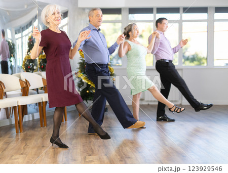 Happy adult people dancing Irish folk dance in row at ballroom on Christmas 123929546