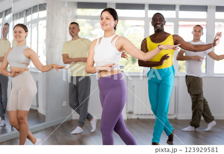 Young Asian woman dancing salsa during group Latin dance class Young Asian woman dancing salsa during group Latin dance class 123929581
