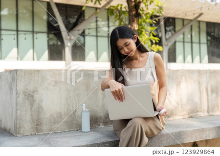 Sustainable habits. Young woman working on her laptop while enjoying the outdoors. 123929864