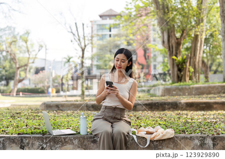 Sustainable lifestyle. Young woman engaged with her smartphone while enjoying nature. 123929890