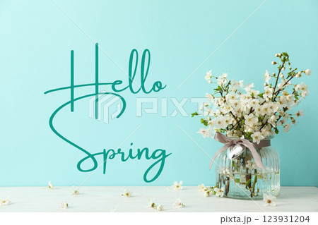 Hello spring, a bouquet of flowering tree branches in a vase on a blue background, with text 123931204