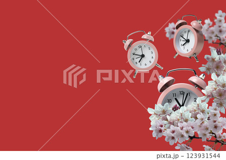 Spring Forward. Pink alarm clocks on a red background, with flowers, with space for text. 123931544