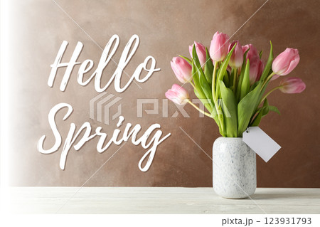 Hello spring, pink tulips in a vase on a brown background with text 123931793