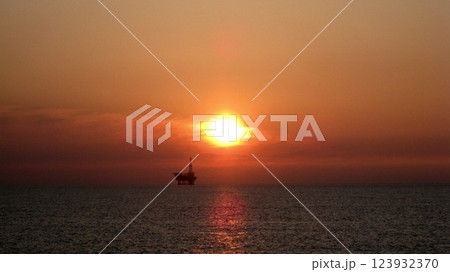 沈む夕日に照らされた海上プラットフォーム 123932370