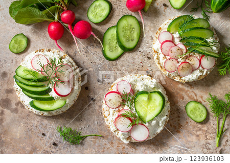 Sandwiches crispbread with ricotta, radish and fresh cucumber on a light or slate countertop. Top view flat lay background. Sandwiches crispbread with ricotta, radish and fresh cucumber on a light or slate countertop. Top view flat lay background. 123936103