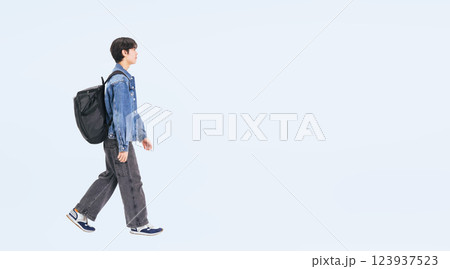 横向きに歩くカジュアルウェアの若い男性の全身写真 123937523
