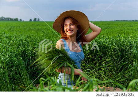 beautiful girl holding a bouquet of ears of green wheat 123938033