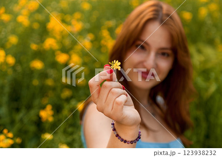 Girl holding a yellow rapeseed flower in the field Girl holding a yellow rapeseed flower in the field 123938232
