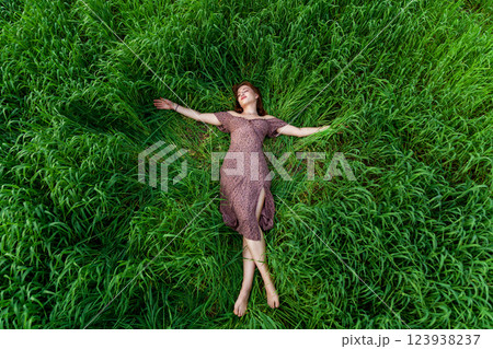 A young girl in a beautiful dress lies in the green grass A young girl in a beautiful dress lies in the green grass 123938237